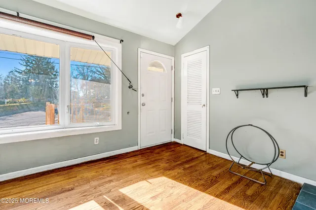 a view of an empty room with window and wooden floor