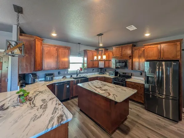 a kitchen with stainless steel appliances kitchen island granite countertop a sink and cabinets