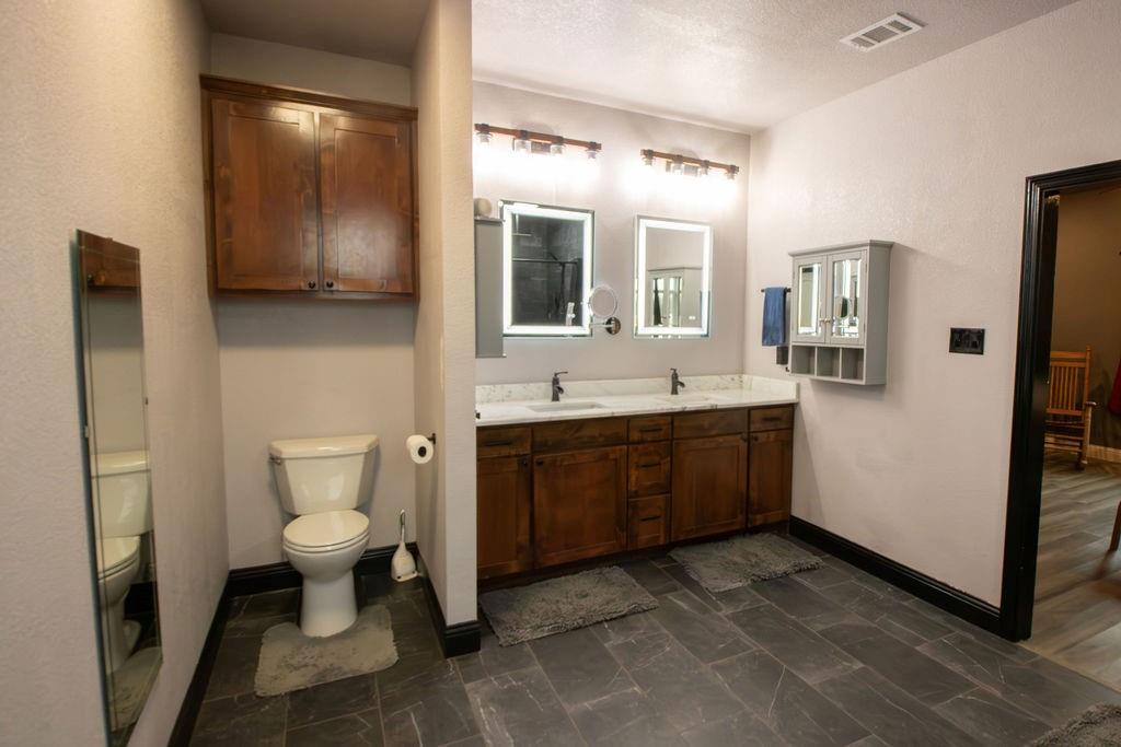 1144 Alamo Road Montague, TX 76251 - Photo 20 of 26 a spacious bathroom with a toilet sink double vanity and mirror