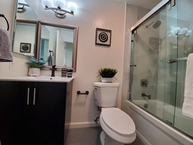 a bathroom with a sink a toilet a mirror and shower