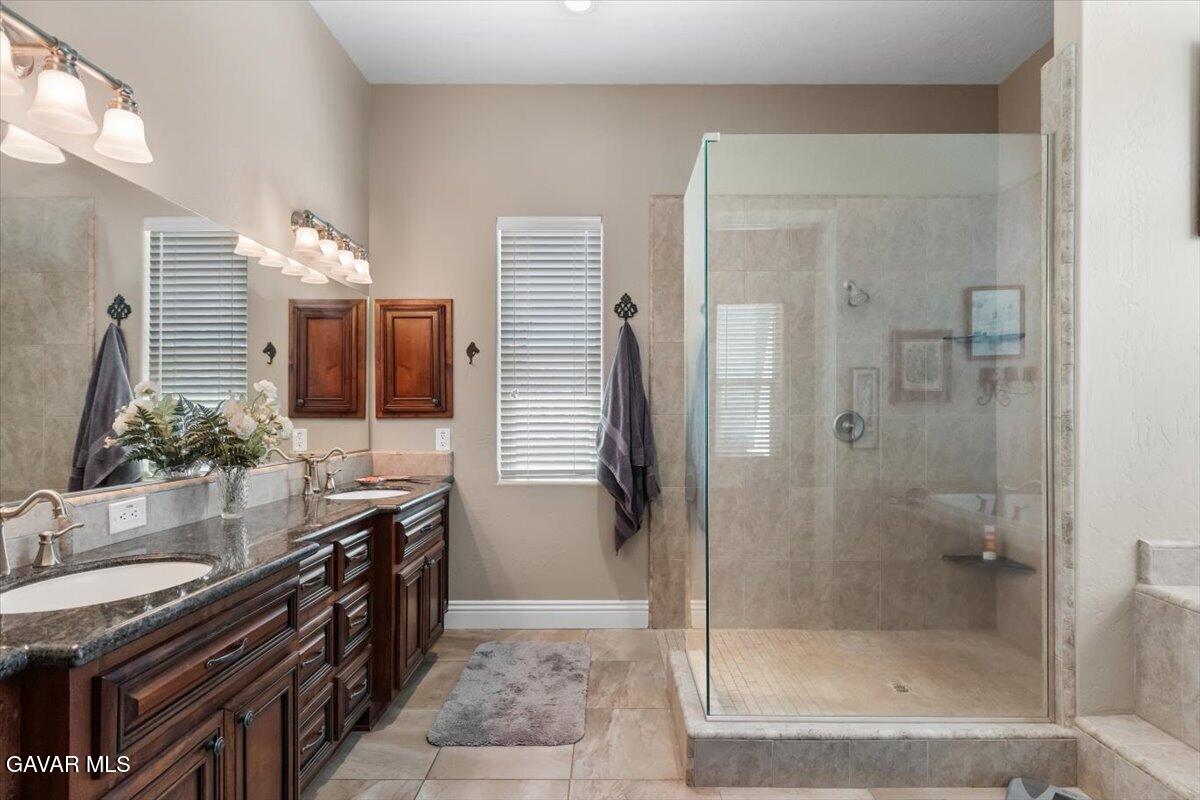 23840 Martingale Way Tehachapi, CA 93561 - Photo 28 of 63 a bathroom with a granite countertop sink a mirror and shower