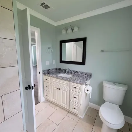 a bathroom with a granite countertop toilet sink and mirror