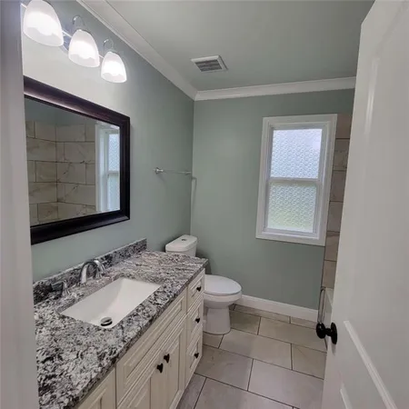 a bathroom with a granite countertop sink a mirror and a toilet