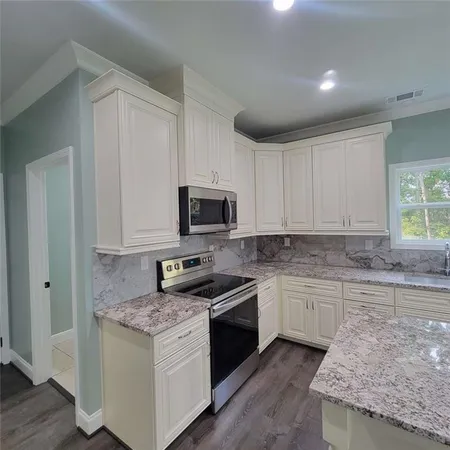 a kitchen with stainless steel appliances granite countertop a stove a sink and a microwave