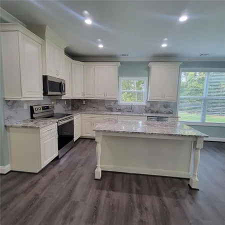 a kitchen with granite countertop wooden floors and white stainless steel appliances