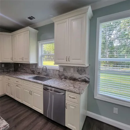 a kitchen with granite countertop white cabinets and a window