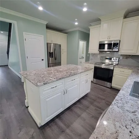 a large kitchen with stainless steel appliances kitchen island granite countertop a stove a sink and a refrigerator