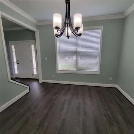 an empty room with wooden floor mirror and windows