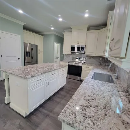 a large kitchen with kitchen island granite countertop wooden cabinets a sink and a white stove