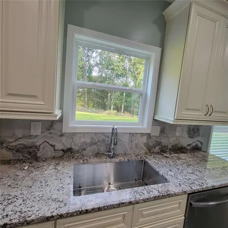 a kitchen with granite countertop a sink window and cabinets