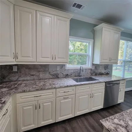 a kitchen with stainless steel appliances granite countertop white cabinets sink and window