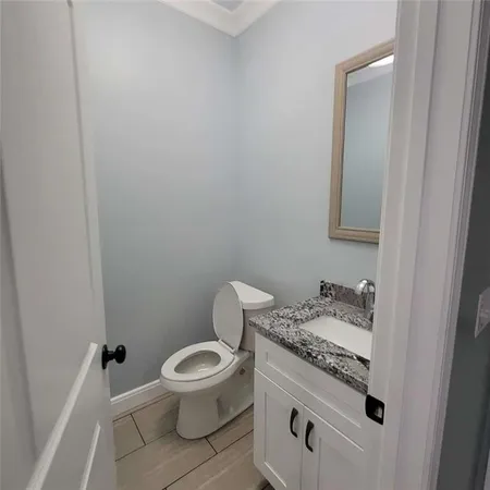a bathroom with a granite countertop toilet and a sink