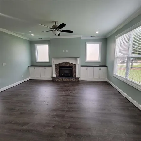 an empty room with windows fireplace and wooden floor