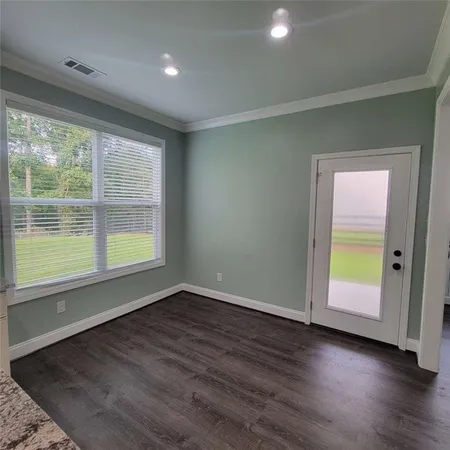 an empty room with wooden floor and windows