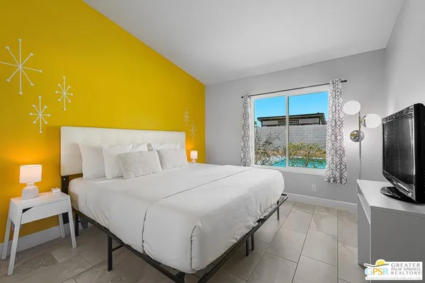 a bedroom with a bed and a flat tv screen on dresser