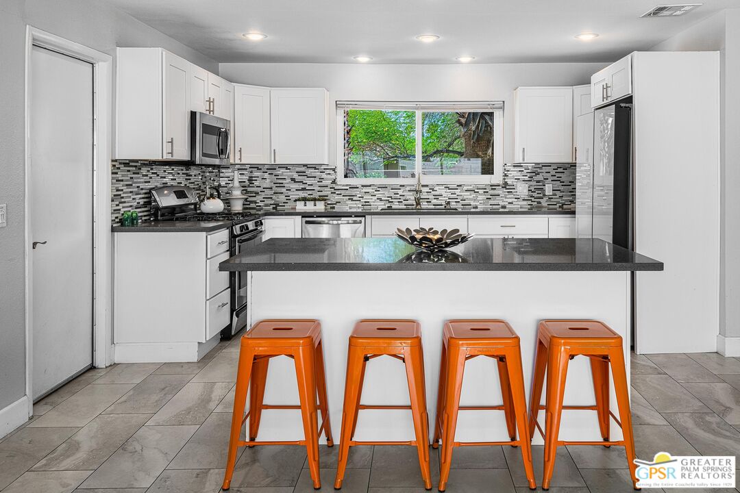 2864 East Valencia Road Palm Springs, CA 92262 - Photo 8 of 31 a kitchen with stainless steel appliances granite countertop a stove a sink and a microwave