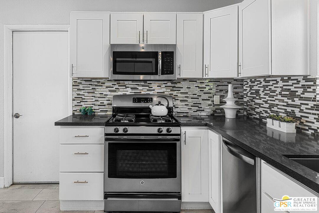 2864 East Valencia Road Palm Springs, CA 92262 - Photo 9 of 31 a kitchen with stainless steel appliances granite countertop white cabinets a stove top oven and sink