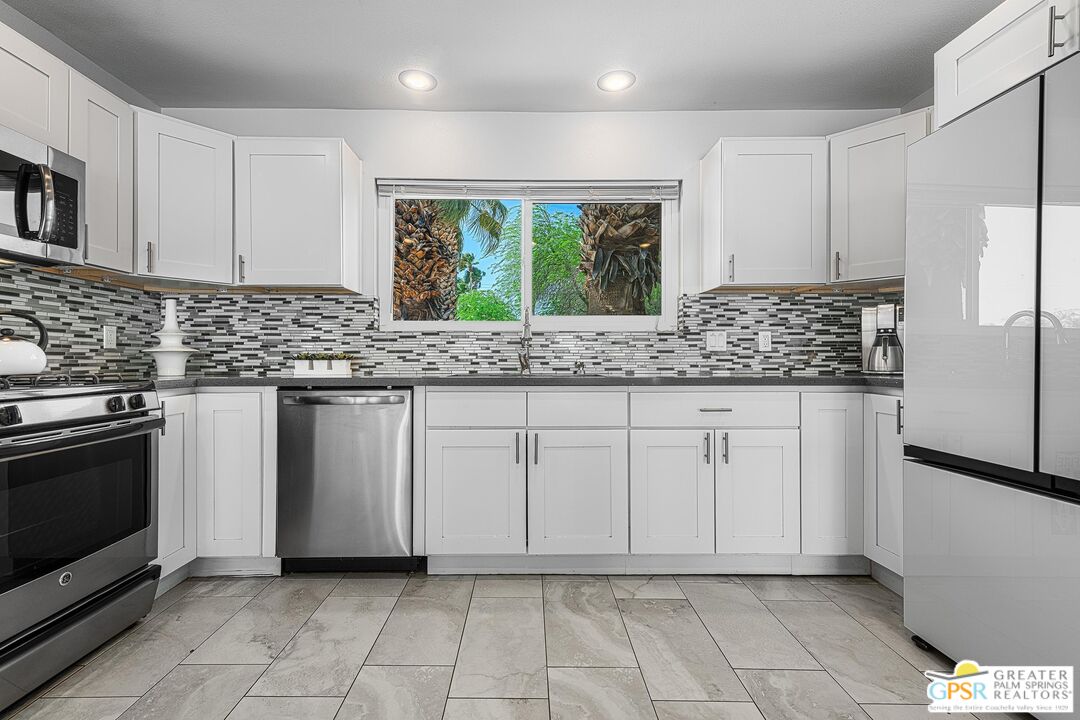 2864 East Valencia Road Palm Springs, CA 92262 - Photo 10 of 31 a kitchen with granite countertop white cabinets stainless steel appliances a sink and a window