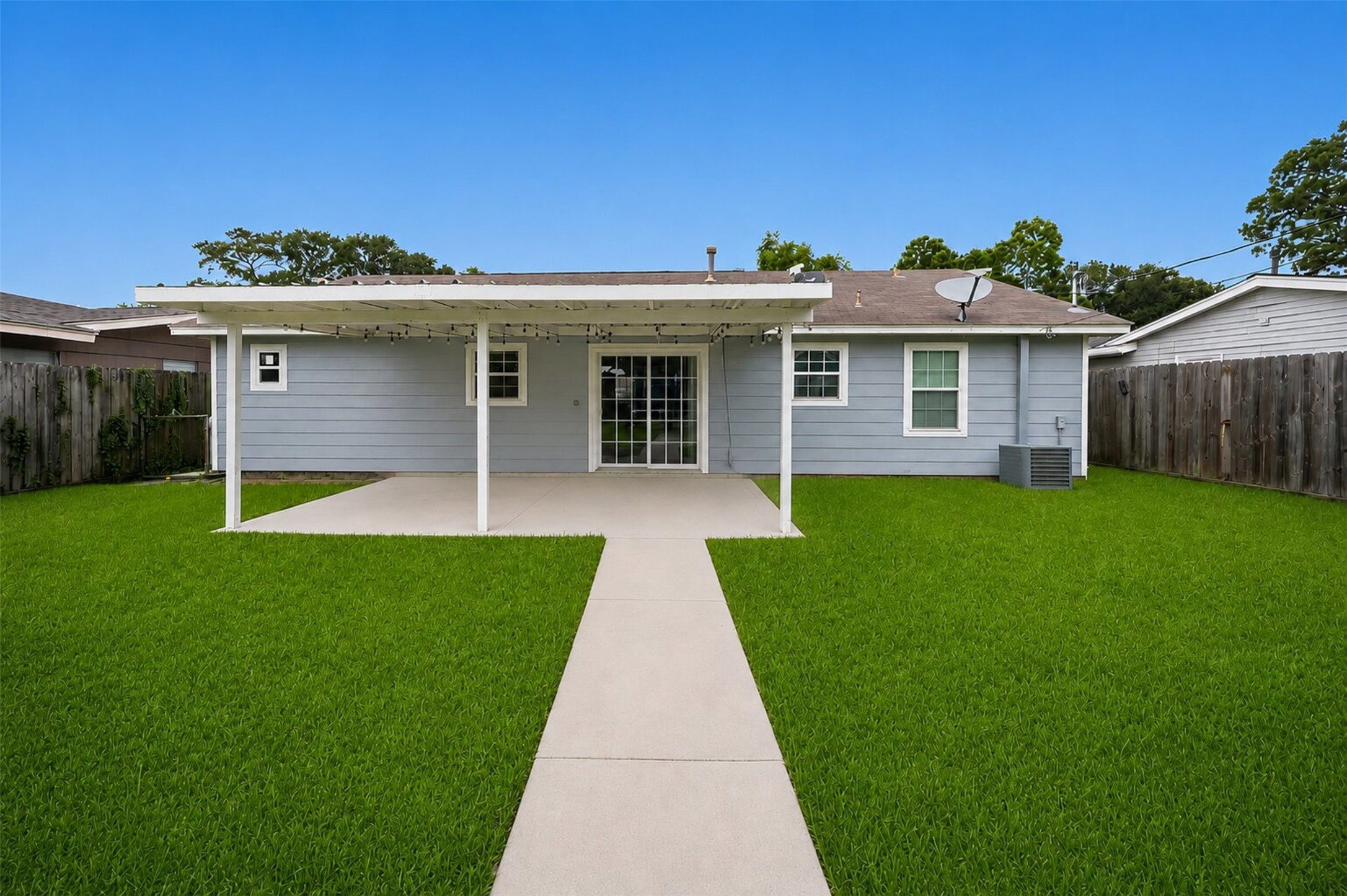 1306 Camden Road Pasadena, TX 77502 - Photo 15 of 16 Spacious backyard retreat featuring a large covered patio with string lights, a lush green lawn, and a fully fenced yard, perfect for entertaining and outdoor fun!
