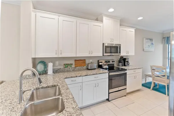 a kitchen with granite countertop a sink stainless steel appliances and white cabinets