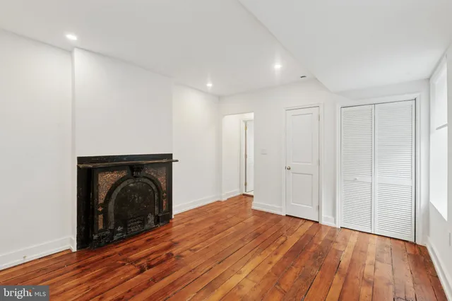 a view of empty room with wooden floor and fireplace