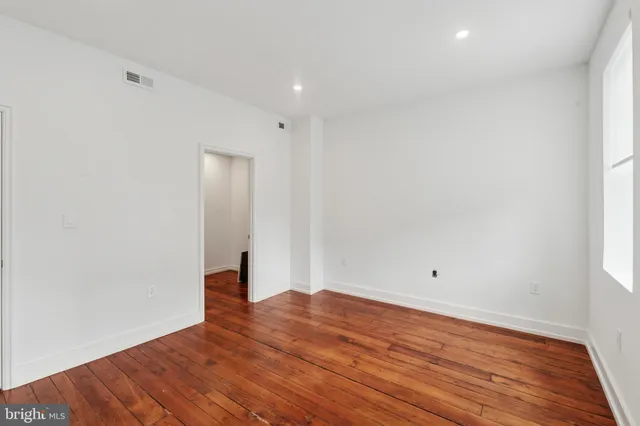 a view of room with wooden floor and white walls