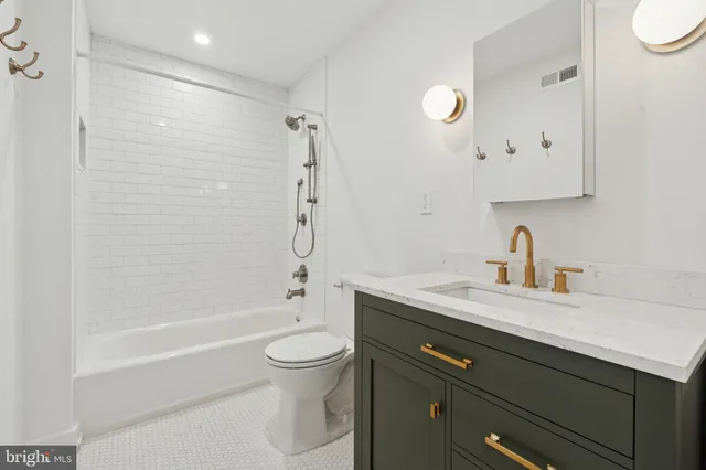a bathroom with a granite countertop sink a toilet and shower