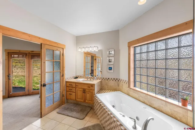 a bathroom with a tub a sink and a large window