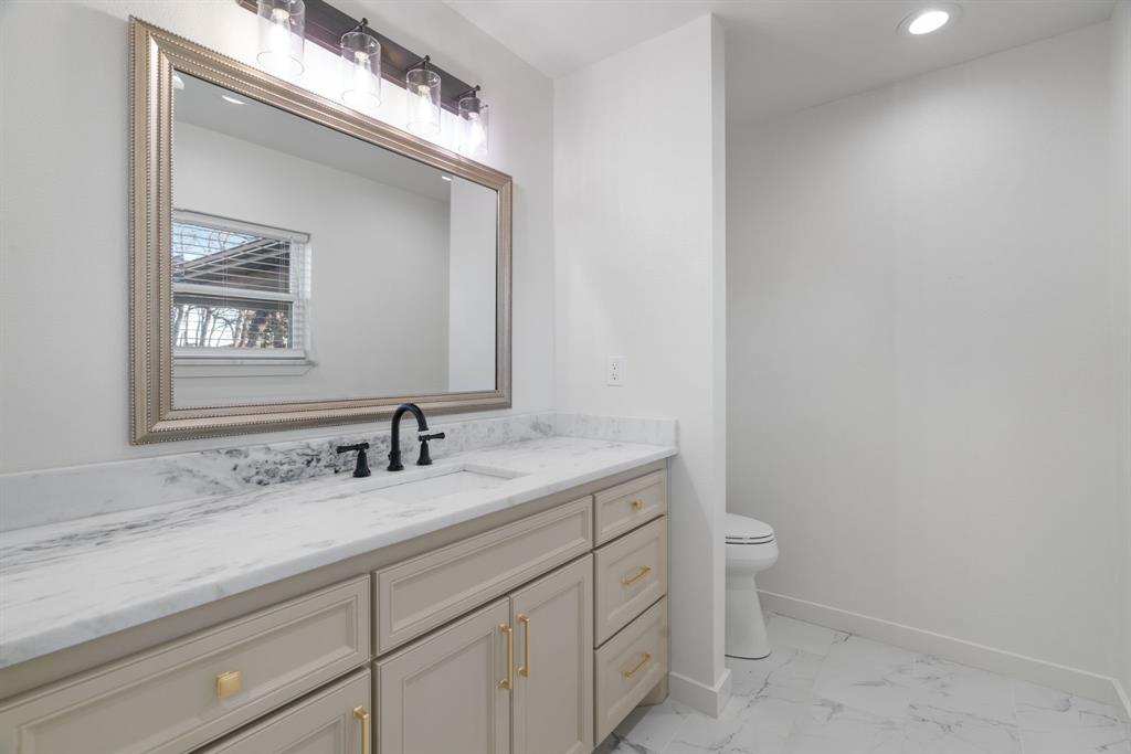 1021 Poe Street Azle, TX 76020 - Photo 26 of 38 a bathroom with a granite countertop toilet sink and mirror