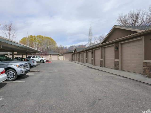 909 South Main Street, Unit F Layton, UT 84041 - Photo 17 of 20 Extensive asphalt parking lot featuring covered parking structures and a row of individual garages with panel doors and stone veneer accents
