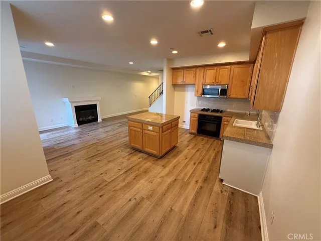 a kitchen with kitchen island granite countertop wooden floors and wide window
