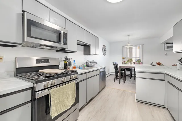 a kitchen with stainless steel appliances a stove a sink dishwasher a microwave oven with cabinets and wooden floor