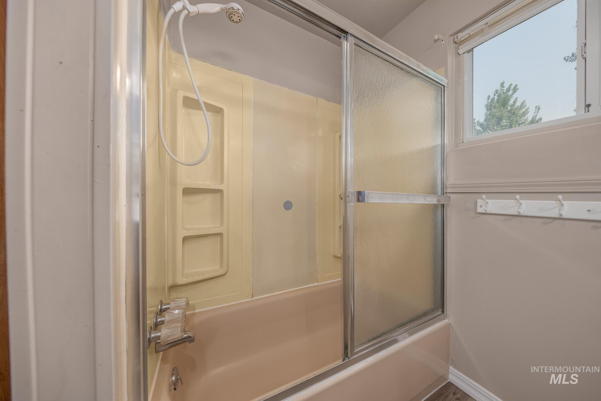1741 Cove Road Weiser, ID 83672 - Photo 28 of 46 Tub and shower combination featuring a sliding glass enclosure, integrated shelving, and a handheld showerhead