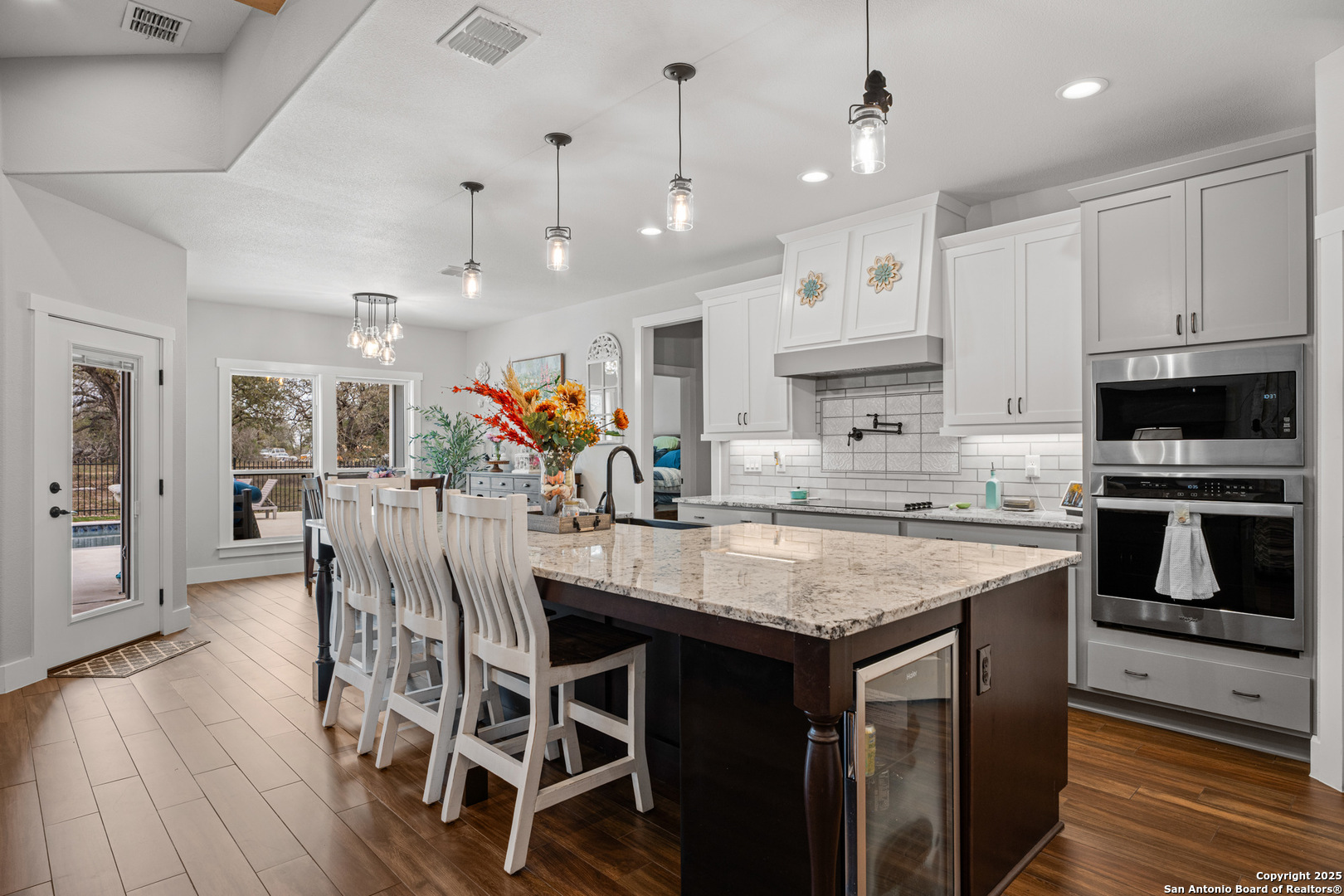 104 Archer Ridge Drive La Vernia, TX 78121 - Photo 11 of 45 a kitchen with stainless steel appliances granite countertop a kitchen island a stove a refrigerator a oven a sink with island chairs and wooden floor