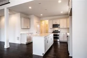 a kitchen with stainless steel appliances granite countertop a stove top oven a sink dishwasher and a refrigerator with wooden floor