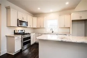 a kitchen with stainless steel appliances granite countertop a stove a sink and a microwave