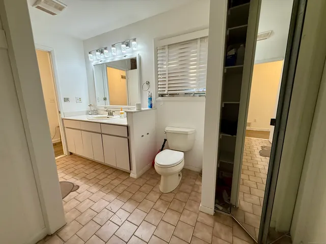 a bathroom with a granite countertop toilet a sink and a mirror