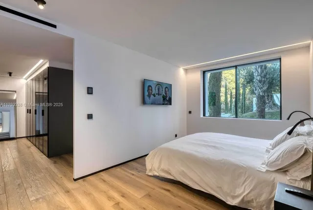 a bedroom with a bed and a flat tv screen on wall
