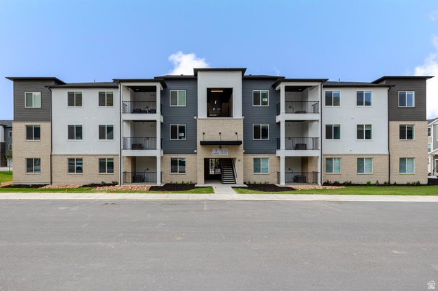 4668 Olive Avenue, Unit T304 Mapleton, UT 84664 - Photo 1 of 16 Multi-level building with brick and siding facade, multiple balconies with dark railings, and a central entryway