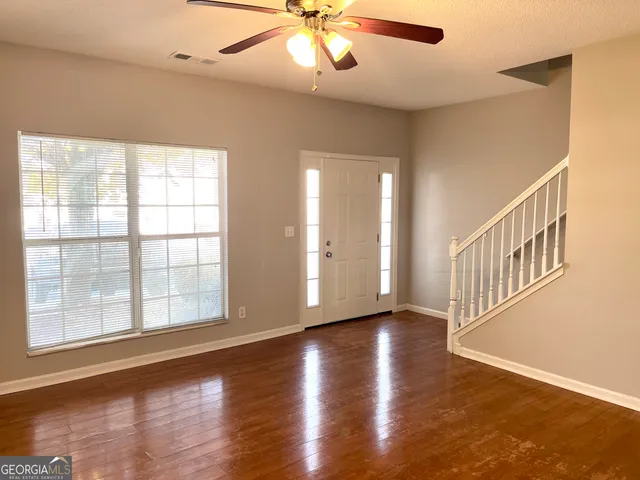 a view of an empty room with wooden floor and a window