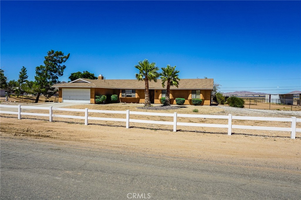 21480 Zuni Road Apple Valley, CA 92307 - Photo 1 of 1 Front of home showing front fence, RV parking to the left of Driveway, mature trees.
