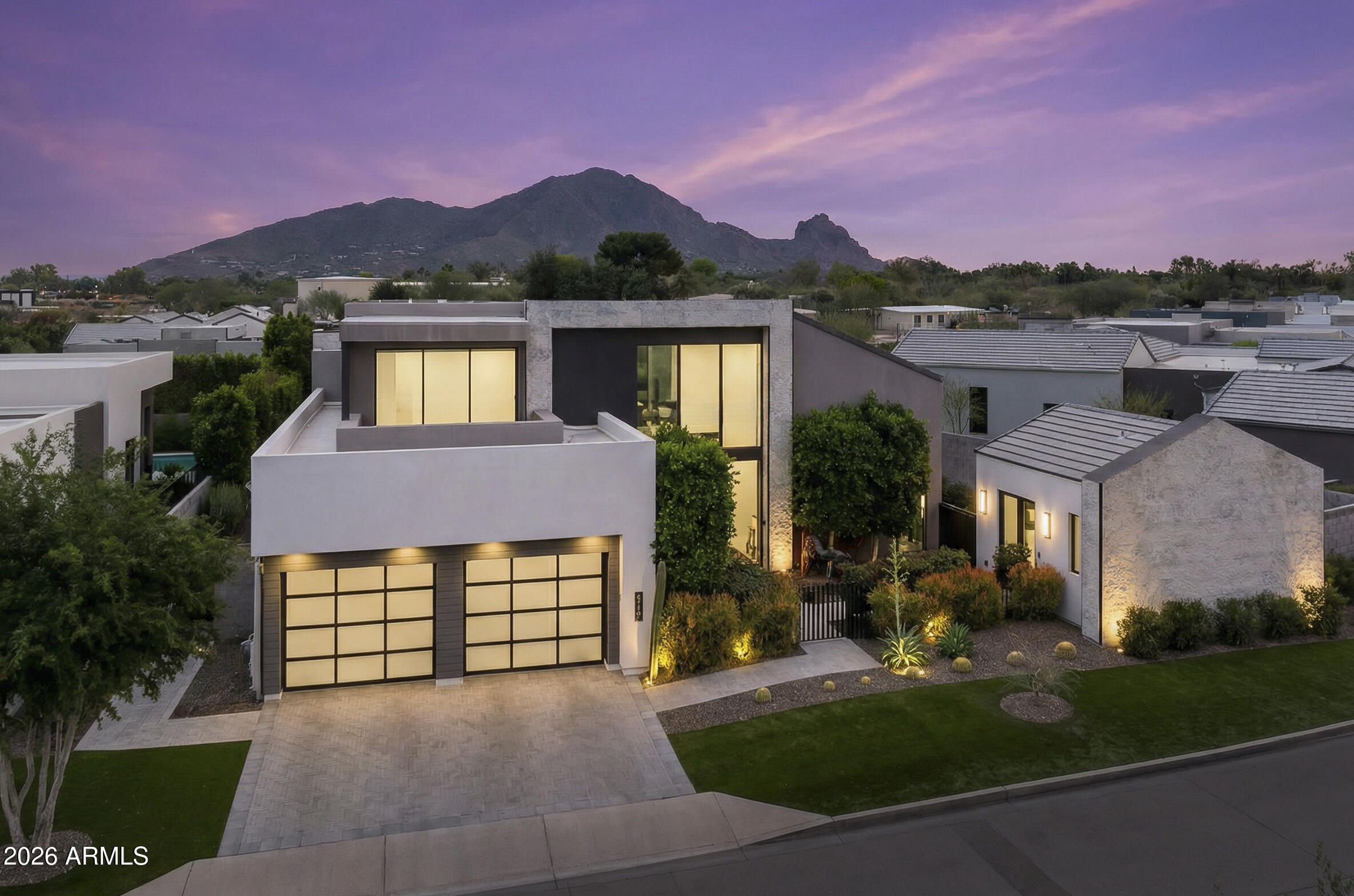 a front view of a house with a yard and mountain view in back