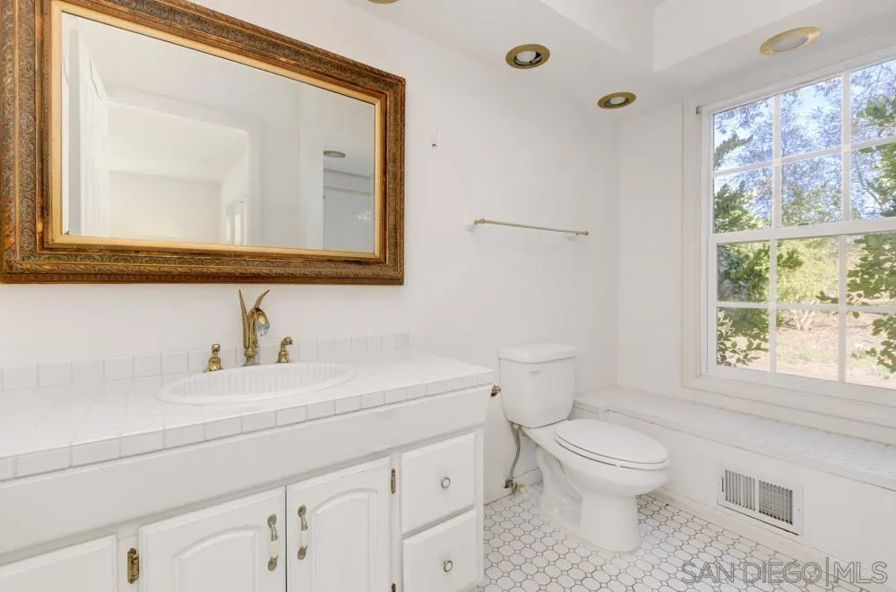 4735 Olive Hill Road Fallbrook, CA 92028 - Photo 21 of 22 a bathroom with a toilet a sink a vanity and a window