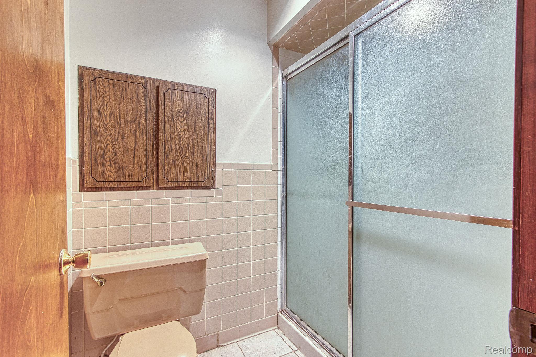12012 Belle River Road Memphis, MI 48041 - Photo 23 of 41 Full bathroom featuring tile walls, a shower stall, light tile patterned floors, and wainscoting