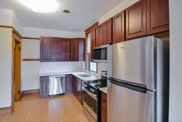 a kitchen with stainless steel appliances granite countertop a refrigerator stove a sink and dishwasher with wooden floor