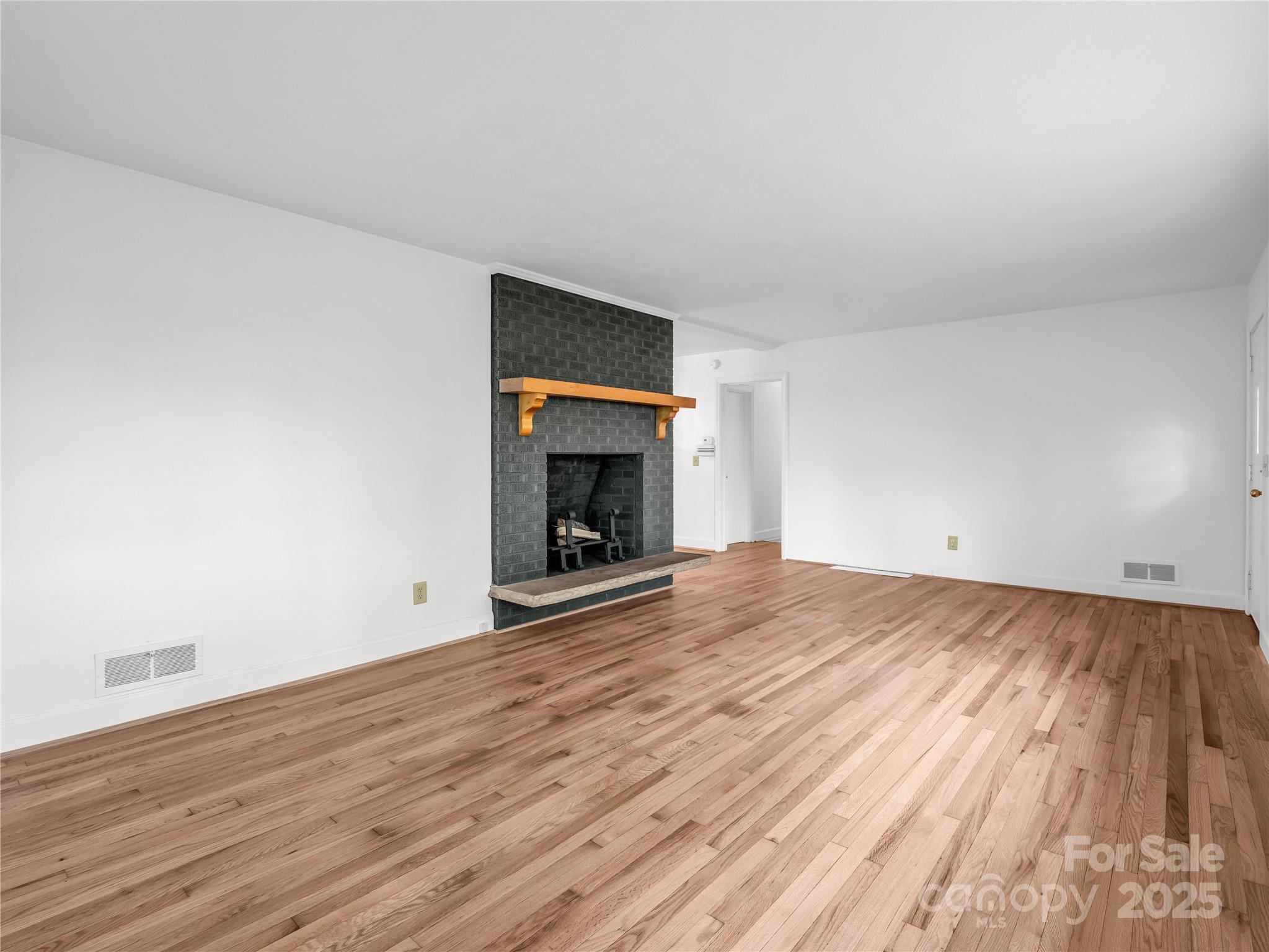 200 Little Wings Mountain Road Columbus, NC 28722 - Photo 13 of 42 a view of empty room with wooden floor and fireplace