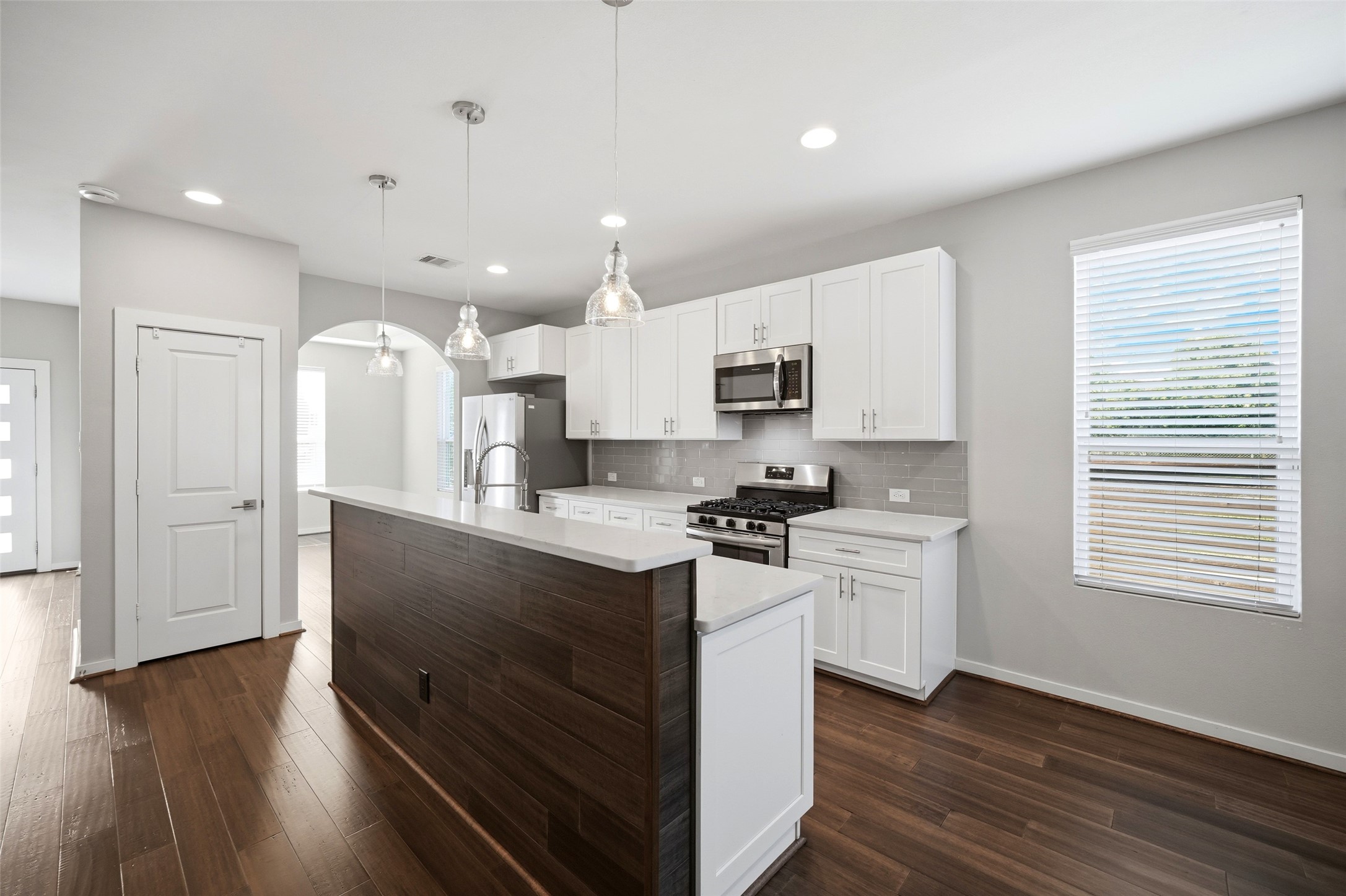 605 Dumble Street Houston, TX 77023 - Photo 18 of 44 a kitchen with stainless steel appliances kitchen island granite countertop a stove a sink a refrigerator and white cabinets with wooden floor