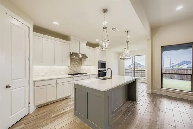 a view of a kitchen with kitchen island a sink stainless steel appliances and cabinets