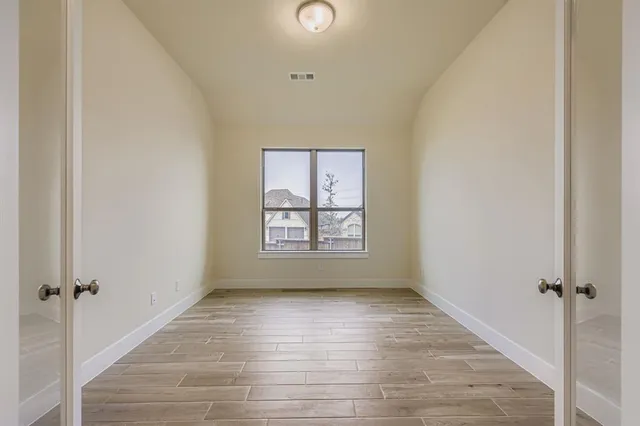 an empty room with windows and a ceiling fan