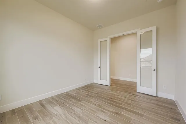 a view of an empty room with wooden floor and closet